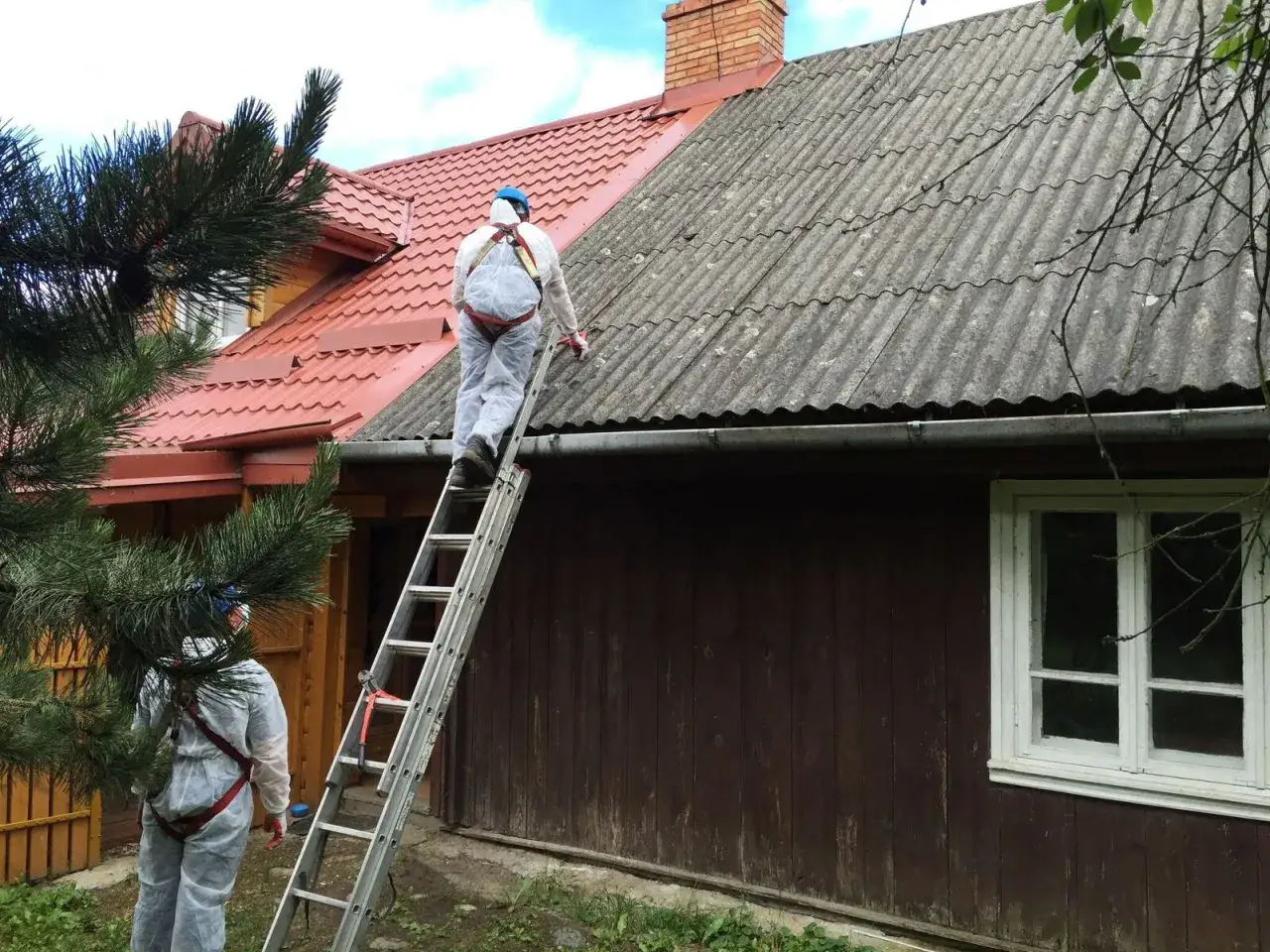 Pracownicy w kombinezonach ochronnych usuwają eternit z dachu. Czy wiesz, co to azbest i jakie niesie zagrożenie?